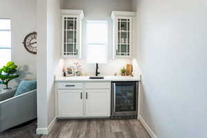 Bar featuring a sink, wood finished floors, wine cooler, indoor wet bar, and baseboards