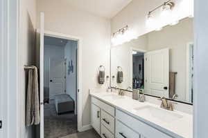 Bathroom featuring double vanity, baseboards, and a sink