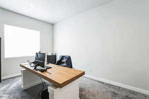 Home office with baseboards and dark colored carpet