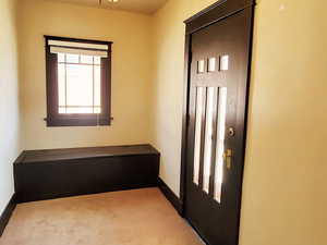 Foyer entrance with carpet flooring and baseboards