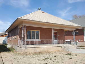 Back of house featuring fence, cooling unit, brick siding, and covered porch