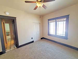 Unfurnished bedroom with a closet, baseboards, carpet floors, and ceiling fan