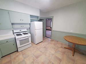 Kitchen featuring wallpapered walls, white appliances, and light countertops