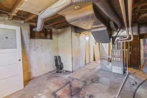Unfinished below grade area featuring gas water heater and heating unit