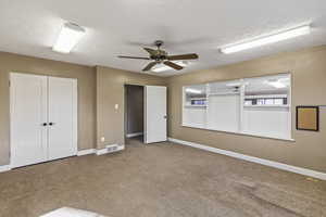 Spare room with carpet flooring, visible vents, a textured ceiling, and baseboards