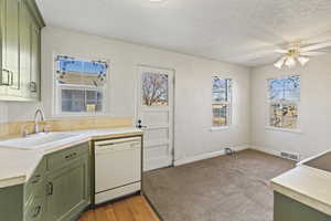 Kitchen featuring green cabinets, dishwasher, visible vents, and a sink