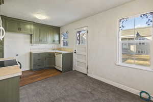 Kitchen with plenty of natural light, light countertops, white dishwasher, and green cabinetry