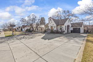 View of front facade with stucco siding, fence, concrete driveway, a garage, and a chimney