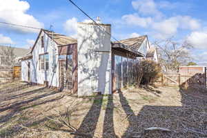 Rear view of house featuring a chimney, concrete block siding, roof with shingles, and fence