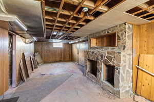 Below grade area featuring a stone fireplace and wood walls