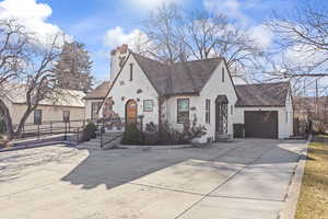 View of front of house with stucco siding, roof with shingles, concrete driveway, a garage, and a chimney