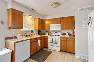 Kitchen featuring white appliances, visible vents, light countertops, and a sink