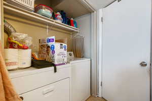 Clothes washing area with laundry area, light tile patterned floors, and washer and clothes dryer