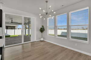 Unfurnished dining area with ceiling fan, light wood finished floors, and a chandelier