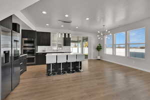 Kitchen with modern cabinets, stainless steel appliances, a breakfast bar area, pendant lighting, and recessed lighting