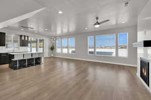 Unfurnished living room featuring a glass covered fireplace, a textured ceiling, light wood-style flooring, a ceiling fan, and recessed lighting