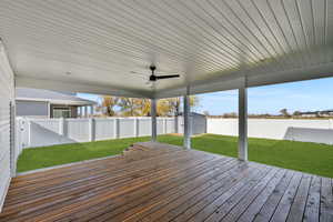 Wooden terrace with a fenced backyard, a shed, and ceiling fan