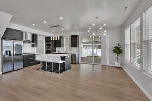 Kitchen with modern cabinets, decorative light fixtures, a breakfast bar, appliances with stainless steel finishes, and a center island