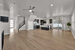 Unfurnished living room with plenty of natural light, stairway, a fireplace, light wood finished floors, and recessed lighting