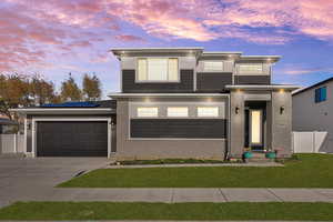 Modern home featuring driveway, roof mounted solar panels, an attached garage, and brick siding