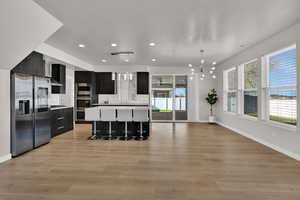 Kitchen with modern cabinets, dark cabinetry, a breakfast bar area, decorative light fixtures, and light countertops