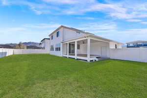 Rear view of house with a ceiling fan, a fenced backyard, and a mountain view