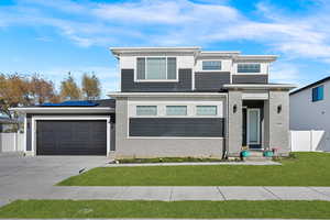 View of front of home with driveway, an attached garage, and solar panels