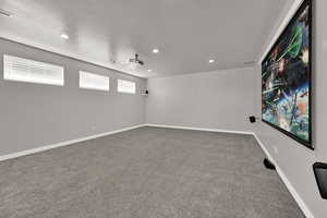 Home theater room with light carpet, recessed lighting, and a textured ceiling
