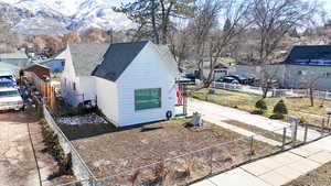 View of property exterior with a fenced front yard, a shingled roof, and a mountain view