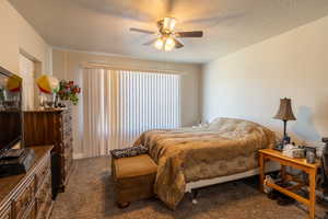 Bedroom featuring a textured ceiling, carpet, and a ceiling fan