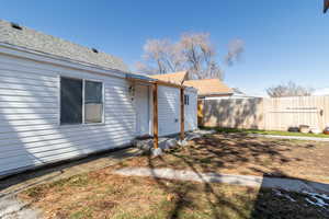 Rear view of house featuring roof with shingles and fence