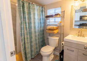 Bathroom with a shower with curtain, a textured ceiling, toilet, and vanity