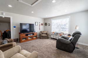 Living room featuring recessed lighting, carpet flooring, a textured ceiling, and baseboards