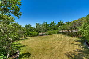 View of grassy yard with golf course view and view of wooded area