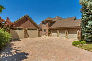 View of front of house with an attached garage, brick siding, driveway, and a shingled roof