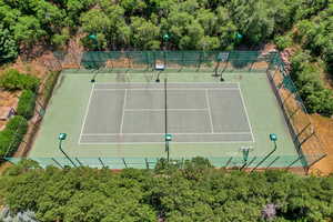 View of tennis court with a forest view