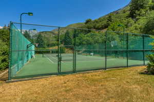 View of tennis court with a gate and a mountain view