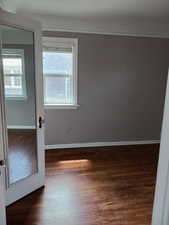 Spare room with baseboards and dark wood-style flooring