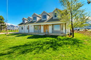 New england style home with a front yard, cooling unit, a porch, and brick siding