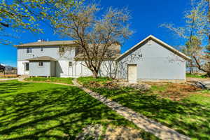 Rear view of house with stucco siding, a yard, and entry steps