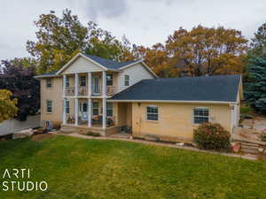 View of front of property with brick siding, a front lawn, fence, covered porch, and a balcony