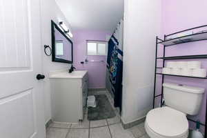 Bathroom featuring baseboards, vanity, toilet, and tile patterned floors