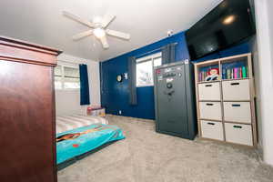 Carpeted bedroom with ceiling fan and multiple windows