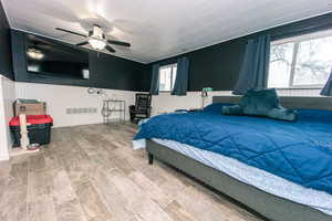 Bedroom featuring wainscoting, visible vents, and wood finished floors