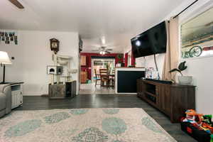 Living area with a healthy amount of sunlight, ceiling fan, and wood finished floors