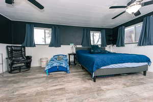 Bedroom with multiple windows, ceiling fan, and wood finished floors