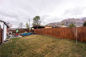 View of yard featuring a patio area, a playground, a fenced backyard, and a mountain view