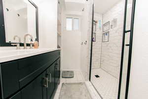 Bathroom with a stall shower, tile patterned floors, vanity, and baseboards