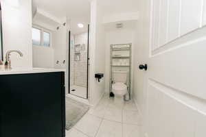 Full bathroom with toilet, vanity, baseboards, marble finish floor, and a stall shower