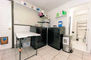 Clothes washing area with washer and dryer, laundry area, and light tile patterned floors